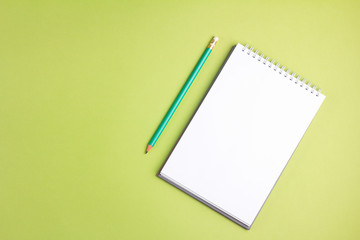 Blank notebook with pencil on green pastel background. Flat lay concept. Copy space