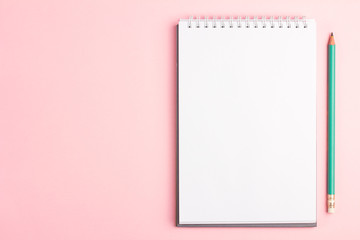 Blank notebook with pencil on pink pastel background. Flat lay concept with copy space