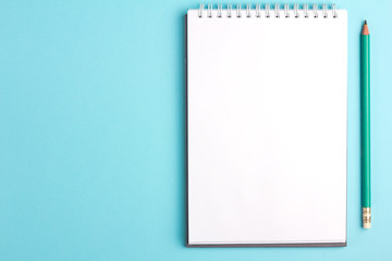 Blank notebook with pencil on blue pastel background. Flat lay concept. Copy space