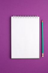 Blank notebook with pencil on purple background. Flat lay concept. Vertical view