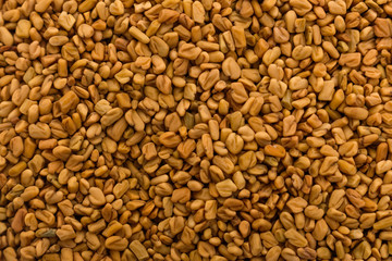 fragrant grains of fenugreek on a rustic background