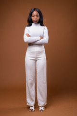 Obraz premium Young beautiful African Zulu businesswoman against brown backgro