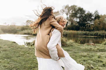 A beautiful couple in free clothes walks in the lawn near the lake on a sunny summer day