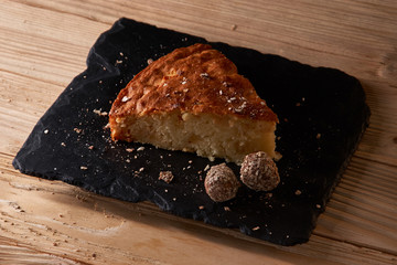 A piece of apple pie with grated chocolate near chocolate truffle candies. Selective focus and small depth of field.