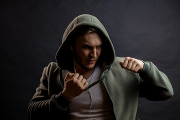 serious young man is fighting with fists. ready to attack. boxer in green hoodie is striking