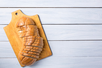 Fresh bread slices on cloth against white wooden background. Top view