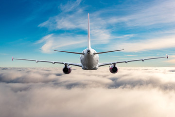 Back view of aircraft in flight. The passenger plane flies high above the clouds and blue sky. Business travel and summer trip concept