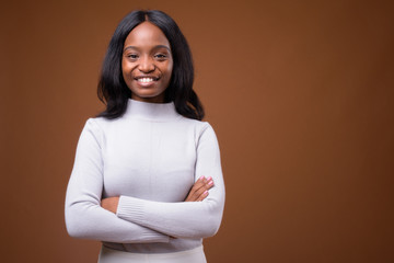 Obraz premium Young beautiful African Zulu businesswoman against brown backgro