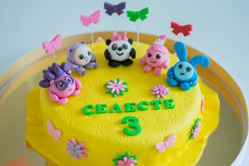 Child colorful birthday cake decorated with little cartoon characters on the top.