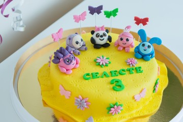 Child colorful birthday cake decorated with little cartoon characters on the top.
