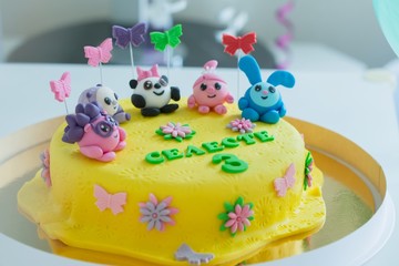 Child colorful birthday cake decorated with little cartoon characters on the top.