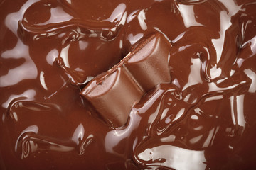 Melted chocolate and pieces of chocolate bar as a background closeup