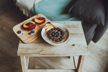 useful nutritious tasty breakfast tiramisu dessert and fresh blueberries berries and peach in a round bowl on a wooden dash board and stepladder, flatlay