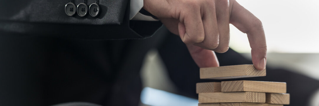 Wide panorama view of businessman placing wooden domino