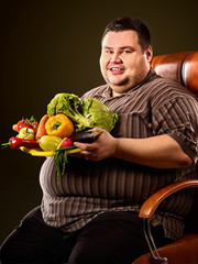 Diet fat man eating healthy food with vegetables cauliflower and sweet pepper with radish, tomatoes...
