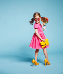 funny child girl fashionista in big mother's   shoes on colored background