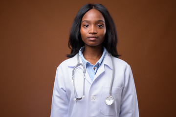 Young beautiful African Zulu woman doctor against brown backgrou