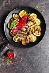 Grilled vegetable salad. Salad of barbecued zucchini, eggplant, sweet pepper, onion and mushrooms on black plate