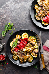 Grilled vegetable salad. Salad of barbecued zucchini, eggplant, sweet pepper, onion and mushrooms on black plate