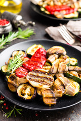 Grilled vegetable salad. Salad of barbecued zucchini, eggplant, sweet pepper, onion and mushrooms on black plate