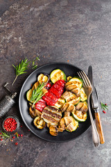 Grilled vegetable salad. Salad of barbecued zucchini, eggplant, sweet pepper, onion and mushrooms on black plate