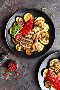 Grilled vegetable salad. Salad of barbecued zucchini, eggplant, sweet pepper, onion and mushrooms on black plate