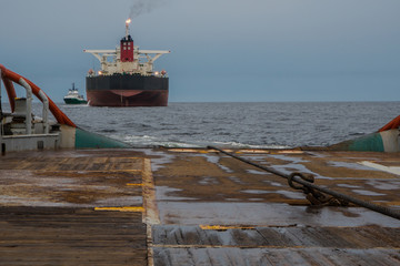 Anchor-handling Tug Supply AHTS vessel during dynamic positioning DP operations near FPSO tanker....