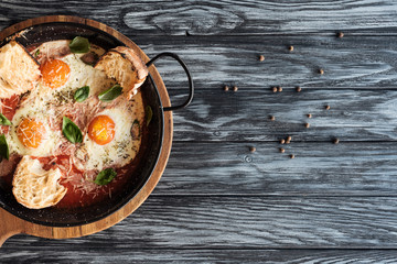 top view of delicious roasted eggs with cheese and peppercorns on wooden table