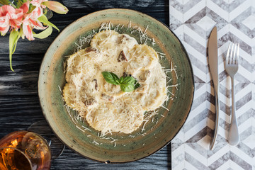 top view of gourmet italian ravioli on plate and fork with knife on wooden table