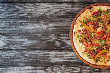 top view of delicious pizza with vegetables, cheese and meat on wooden table with copy space