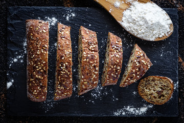 Closeup of bread with flour on slate bottom. Top view. Dark Food