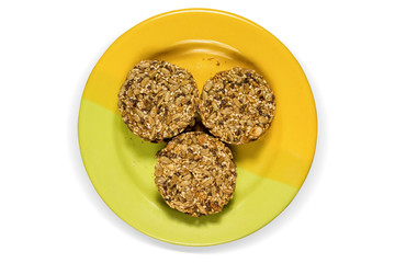 Three cookies made of sun flower seeds on yellow plate on white background, isilated.