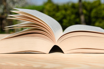 Book on a wooden table. Cards moved by the wind.