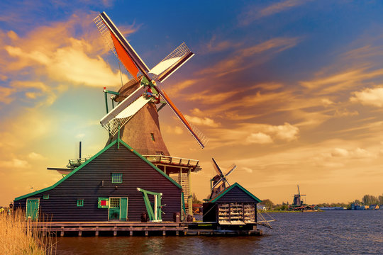 Dutch typical landscape. Traditional old dutch windmills against blue cloudy sky in the Zaanse Schans village, Netherlands during sunset. Famous tourism place.