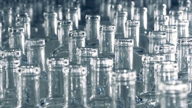 Necks of slowly moving glass bottles in a close up