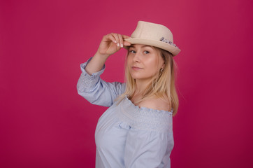 Woman in straw hat and blue dress. Stylish woman in casual clothes. Isolated on pink studio background. Summer holidays, recreation and vacation concept.