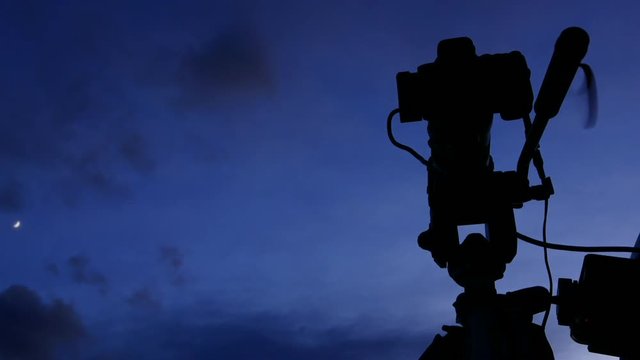 Professional camera against evening sky taking film video or shooting images pictures. Time lapse 4K.