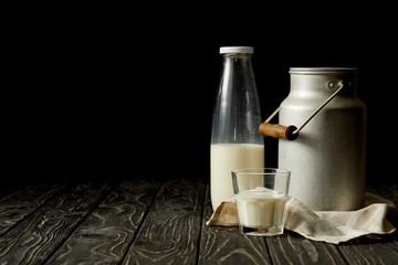 milk in bottle, glass and aluminium can on sackcloth on black background