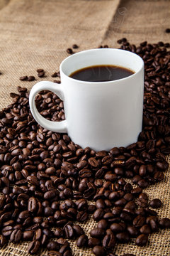 White coffee mug with coffee beans on hessian sack cloth