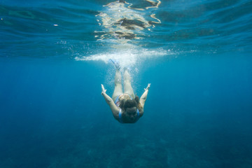 underwater photo of young woman in swimming suit diving in ocean alone - Powered by Adobe