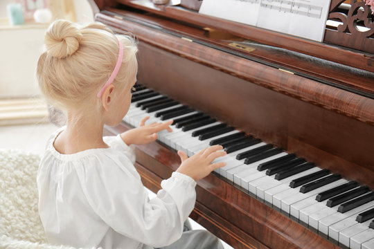 Little girl playing piano indoors