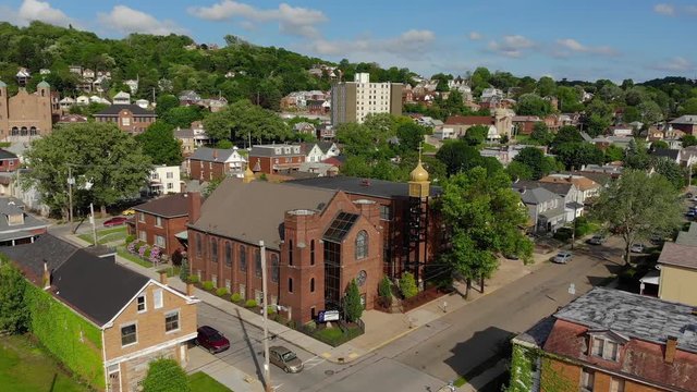 A daytime slow moving forward aerial establishing shot of a church in the residential district of a small New England town. Pittsburgh suburbs.  	