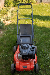 Lawn mower stands on grass on lawn in back yard in the summer.