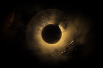 Music concept. Freezelight glowing vinyl on dark background or Turntable playing vinyl with glowing...