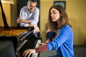 Two young women at a piano time with a teacher