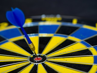 blue, yellow dart board and arrow that hits the target