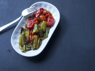 fried green pepper and tomato on wood in white plate