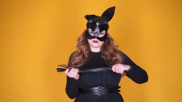 Provocative girl in leather bunny mask holding flogging whip