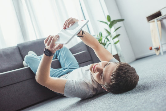 teenager using digital tablet while lying on floor