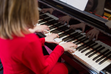 Hands of two women playing the piano.